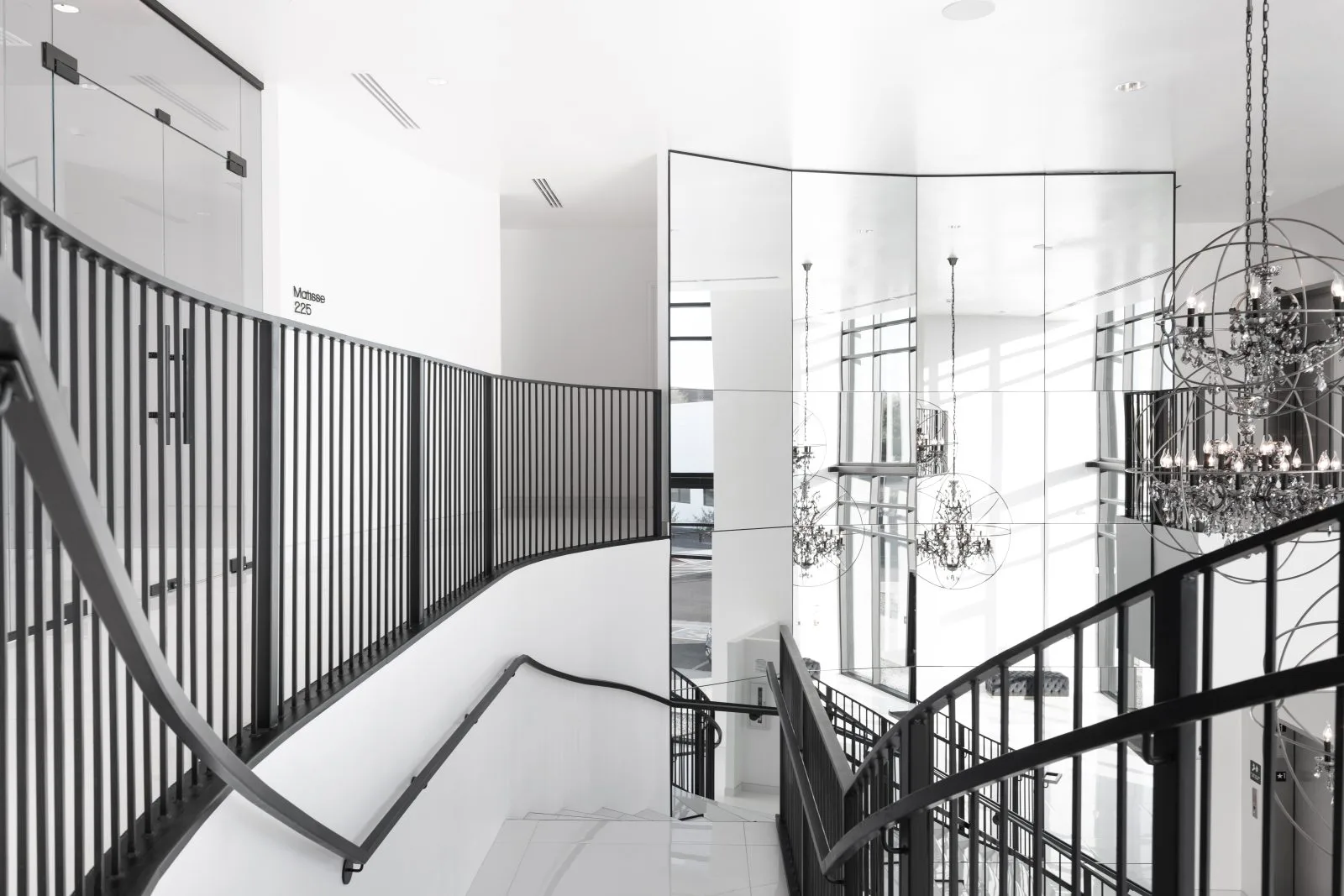 Modern medical office staircase with metal railings and chandelier in bright, minimalist interior